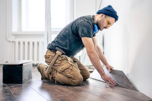 a-male-worker-puts-laminate-flooring-on-the-floor-9H6X32G.jpg